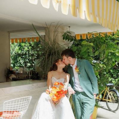 Bride and groom share a kiss sitting outside at their sunny wedding day at Parker Palm Springs