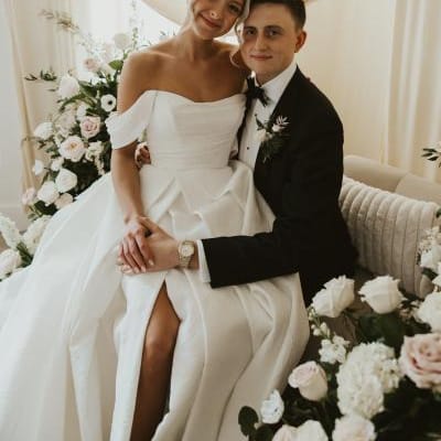 Bride sits on groom's lap in romantic lounge vignette on wedding day at Woodhaven