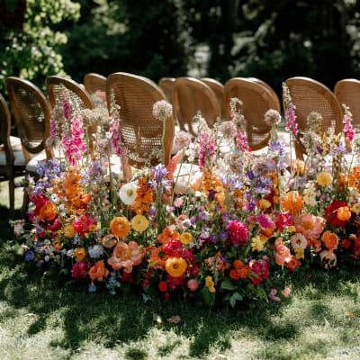 Bold abundance of blooms line the outdoor aisle in wedding day at Fox Hollow Farms