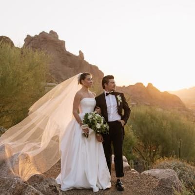 Bride and groom pose on the rocks of Camelback Mountain with the golden hour casting a glow behind them