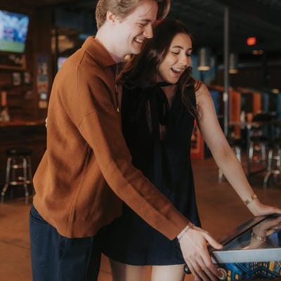 Olivia and Erik play arcade games in their engagement session with Caitlin & Camera