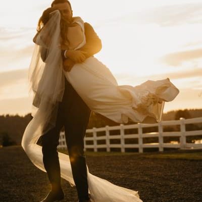 Connor picks up and twirls Katie on the grounds of Fiddler's Bluff on their wedding day