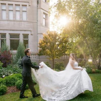 Jackson holds Grace's train as they walk across the grounds of American Swedish Institute