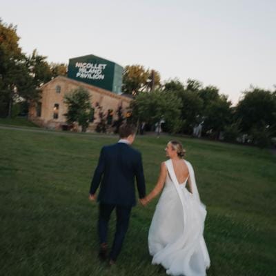 Abby and Caleb walk on the grounds of Nicollet Island Pavilion on their wedding day