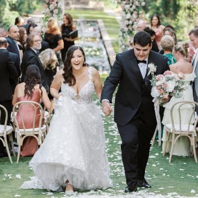 Samantha and Ryan cheer as they walk back down the floral-lined aisle at Sierra Madre