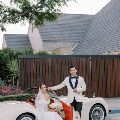 Olivia and Blaec pose in a vintage getaway car