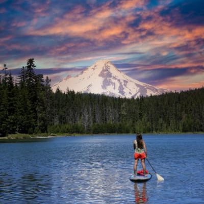 Paddle boarder on a lake with mountain in the background