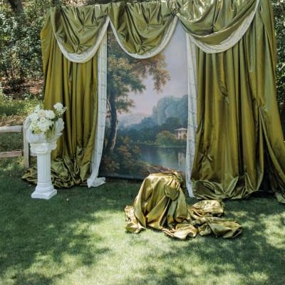 Outdoor photo-op featuring green drapery and a painted scene