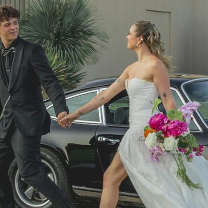 Groom leads bride across grounds of Maryhil Museum, a vintage car in the background