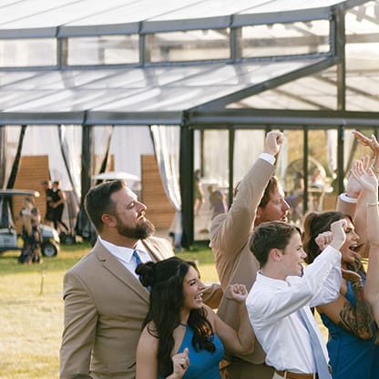 Monica and Matt kiss as their wedding party cheers on in celebration at private residence
