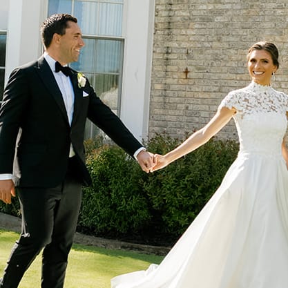 Bride and groom hold hands while walking the grounds of the Milwaukee Country Club