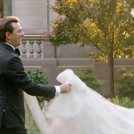 Jackson holds Grace's train as they walk across the grounds of American Swedish Institute