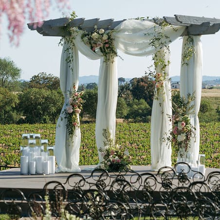 Styled ceremony scene featuring pink florals and white draping against the rolling hills of Mira Vista Estate