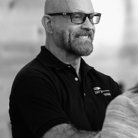 Black-and-white portrait of Art of Catering owner Eric Sandstrom wearing glasses and a black polo shirt
