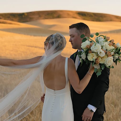 Abbey and Peter pose in golden fields of wheat on their wedding day