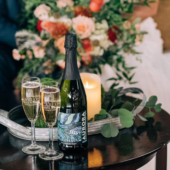Couple sit with glasses of wine and bottle from Carlos Creek Winery