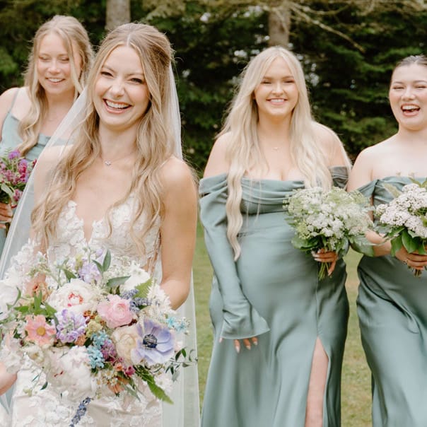 Bride walking the grounds of Woodland Meadow Farms alongside her sage-clad bridesmaids