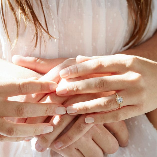 A couple holds hands; the bride wears a lab-grown halo ring