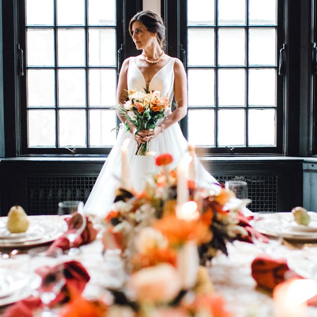 The bride stands at the head of a table bedecked with fall foliage in a grand room at The University Club of Portland
