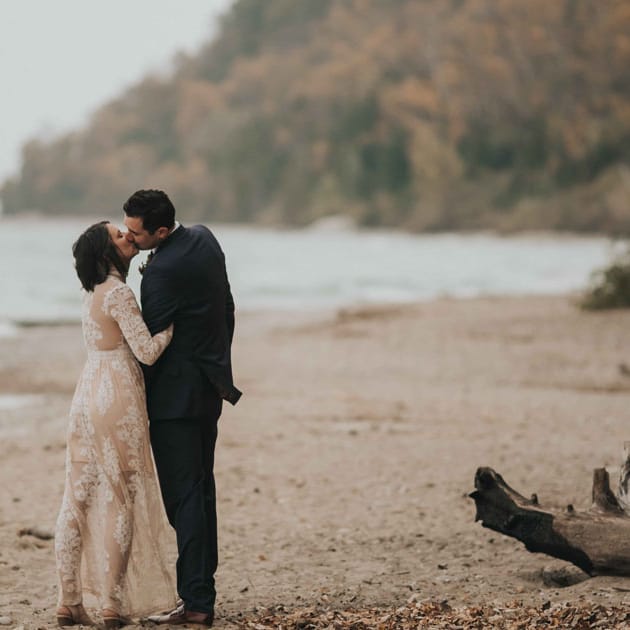 The bride, wearing Free People, kisses her groom on the beach at Grant Park