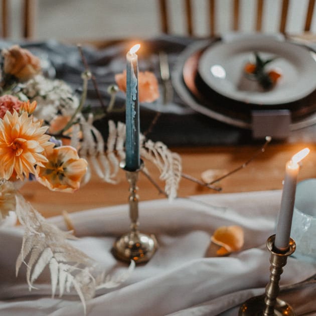 Orange blooms bedeck a table with blue tapers and flowing linen