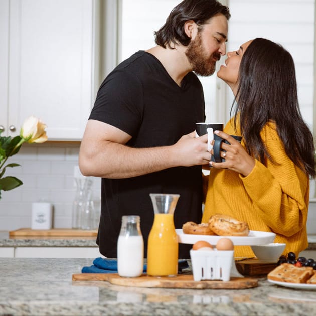 Bride and groom stand in their kitchen at breakfast for their engagement photography session.