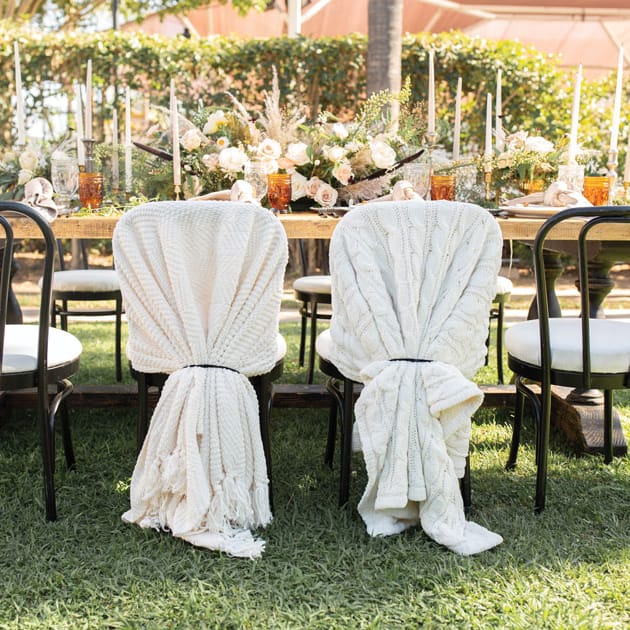 The bride’s and groom’s chairs are wrapped in hygge cable-knit blankets.