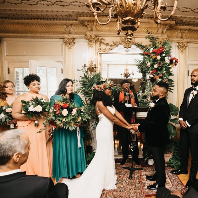 Heather Ensley and Charles Kidd II at their ceremony with their bridal party and tropical florals.