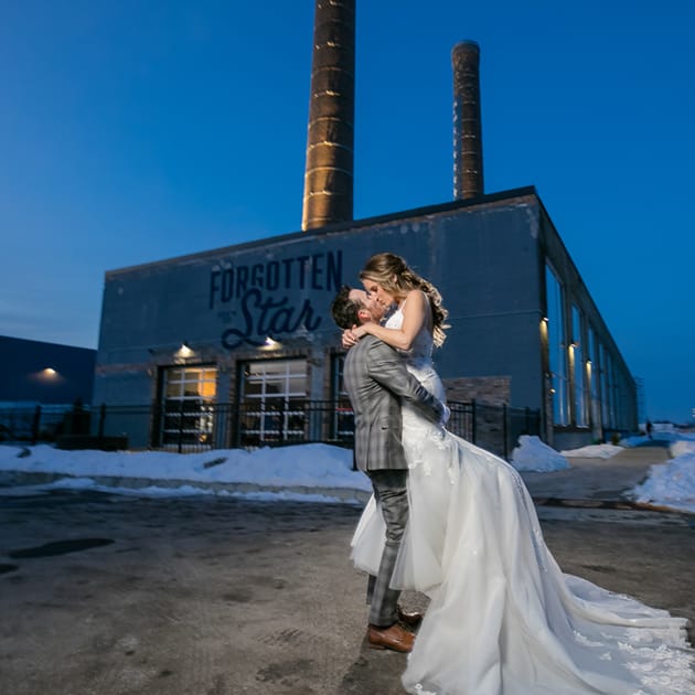 Newlyweds kissing outside of Northern Stacks wedding venue. 
