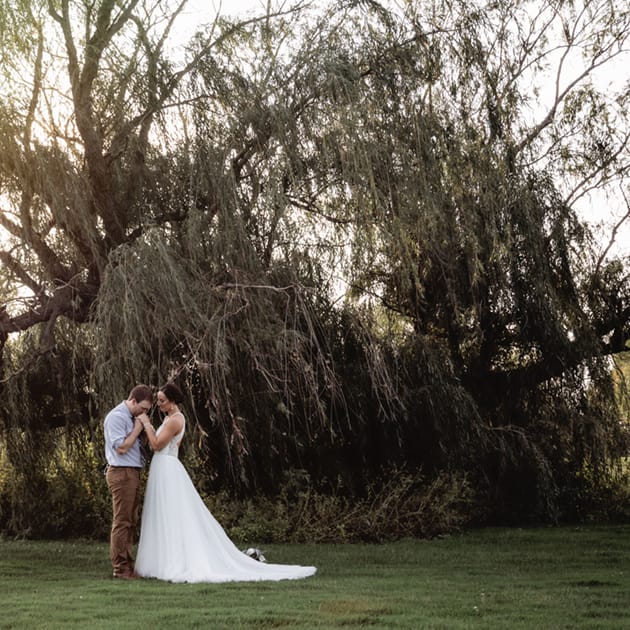 Newlyweds Haley and Alex in front of a willow tree at Green Lake Bible Camp