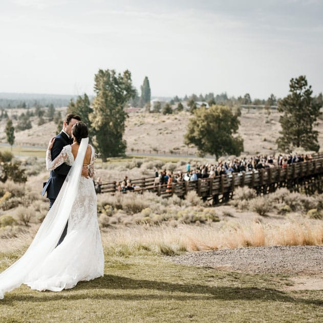The hills and valleys of Central Oregon span beyond the couple as they pose at Brasada Ranch