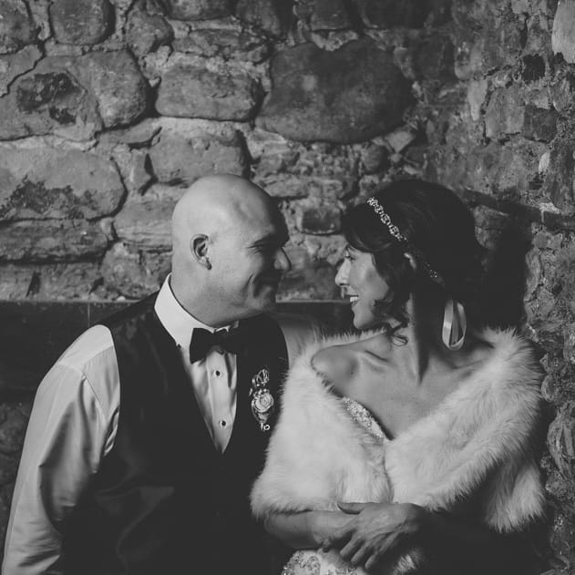 The bride and groom stand against exposed limestone at the Liar's Club in their Art Deco attire.