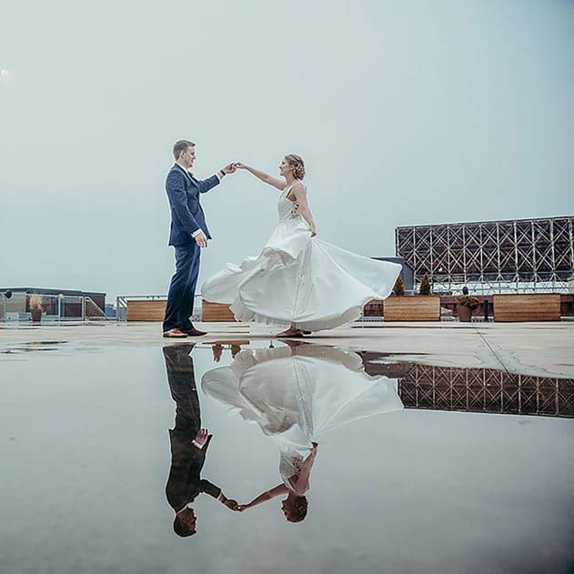 Bride and groom dance over a reflective puddle on the rooftop of A'BULAE.