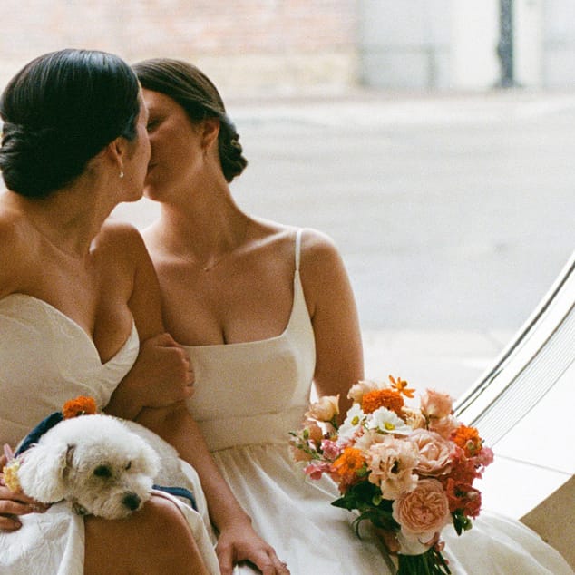 Close up of Caroline and Amy cozy up with their dog on their wedding day at Overture Center for the Arts