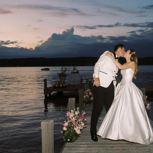 Bride and groom share a kiss against the sunset on Pewaukee Lake