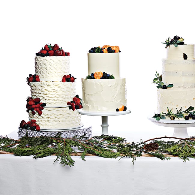 Three tiered, buttercream wedding cakes with fruit.