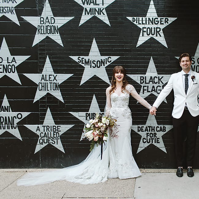 Sarah and Scott pose for a wedding photo in front of First Avenue.