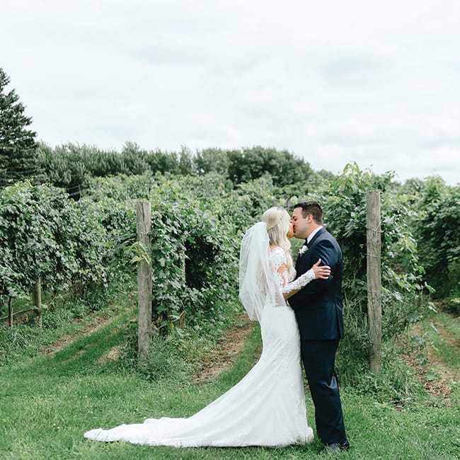 Tom and Chelsey kiss on their wedding day at Round Lake Vineyards & Winery
