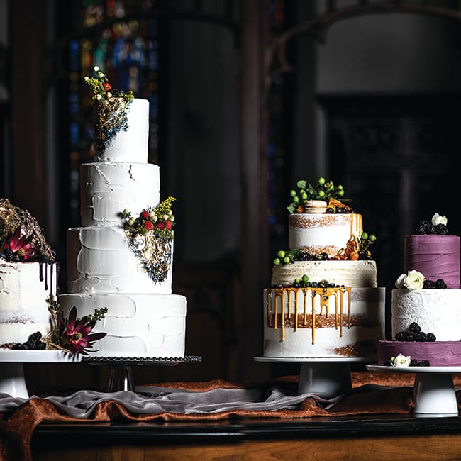 Four tiered wedding cakes with floral decorations and fruit toppings.