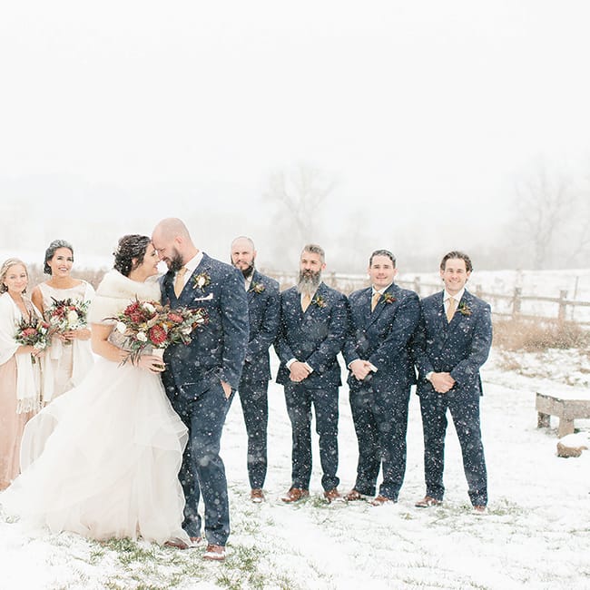 Maggie Christie and Jeremy Kocher kiss in front of their wedding party at The Enchanted Barn.