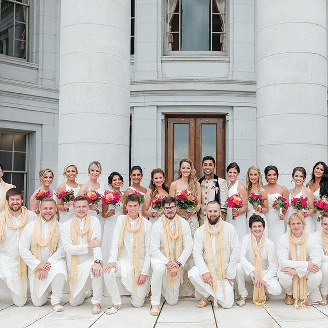Molly Stiffler and Bobby Syal pose with their wedding parties. The groom and groomsmen wear traditional Indian dress.