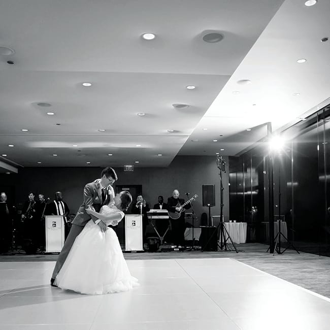 A couple performs their first dance at their wedding while a band plays in the background.