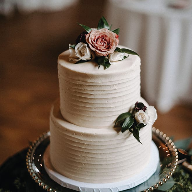 A two-tier white wedding cake with floral decorations.