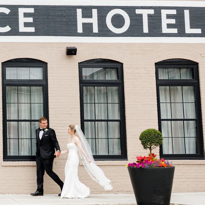 Colette and Dylan walk outside of The Confluence Hotel on their wedding day