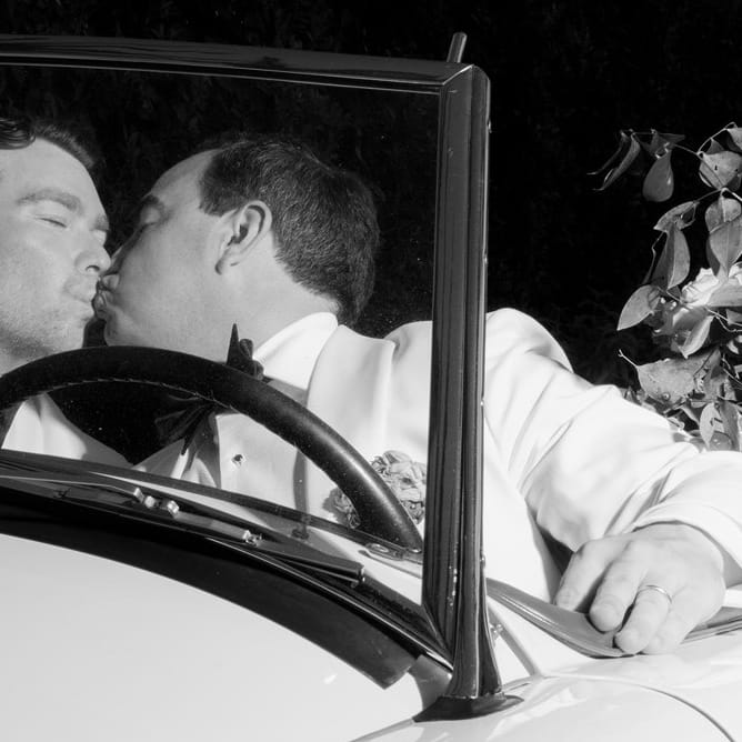 James and Timmy share a kiss in their floral decorated vintage getaway car