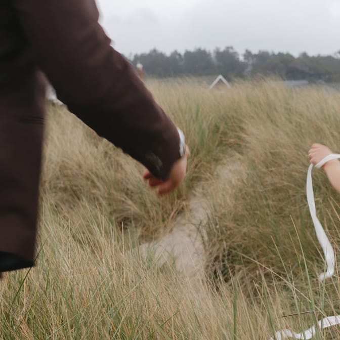 Mykayla and Jake run through the beach grass during their elopement session