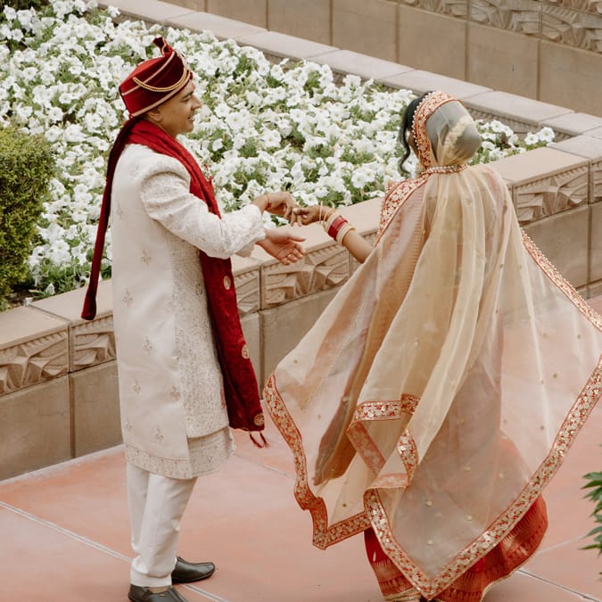 Nikita and Sahil walk hand in hand amidst the courtyard at the Arizona Biltmore on their wedding day