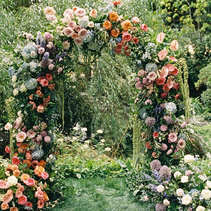 Lush floral arch against willow trees on grounds of Chateau Lill