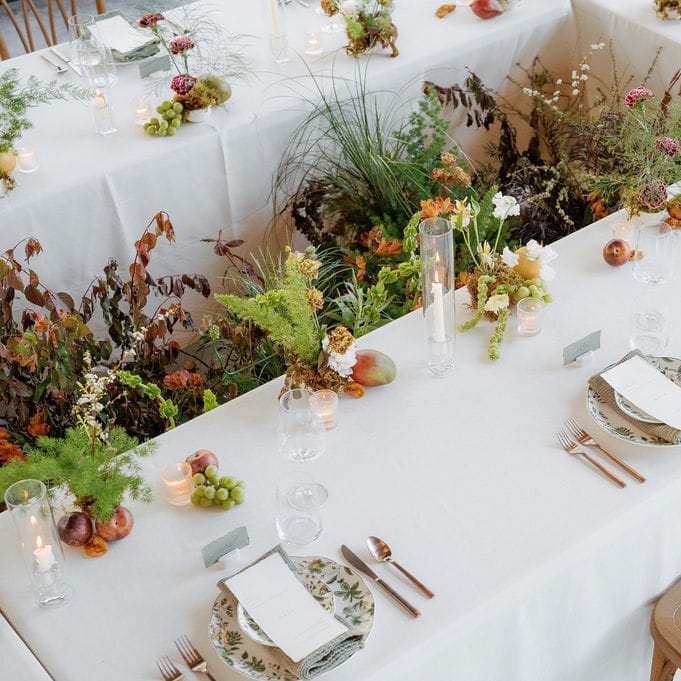 Organic florals in the middle of a rectangular table featuring simple, elegant design in glass house reception space at Woods & Co