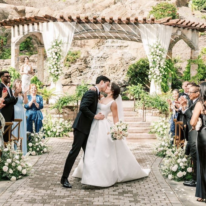 Bride and groom share a kiss at the end of the aisle after exchanging vows in outdoor ceremony at Villa Loriana